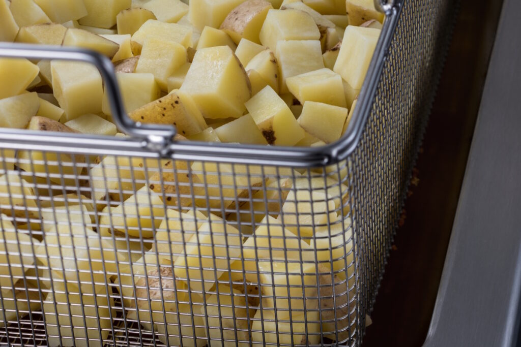Чому картопля фрі не хрумка, а молода — розвалюється? Ось справжня причина 3 Нарізана кубиками картопля у кошику після варіння